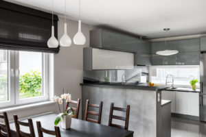 Simple dining set, decorative pendant lamp and roller blinds, light open kitchen in the background